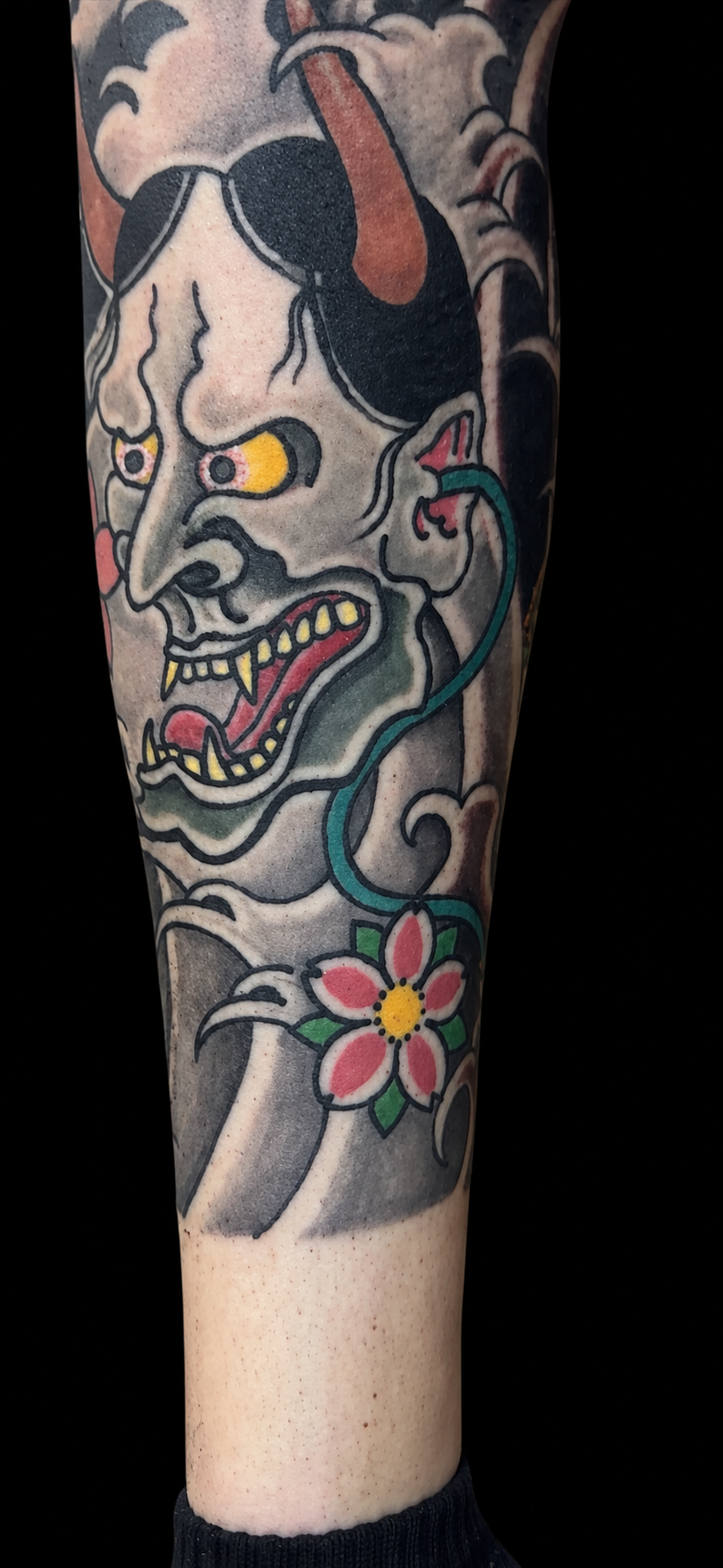 Japanese namakubi forearm tattoo with cherry blossom on a solid black background