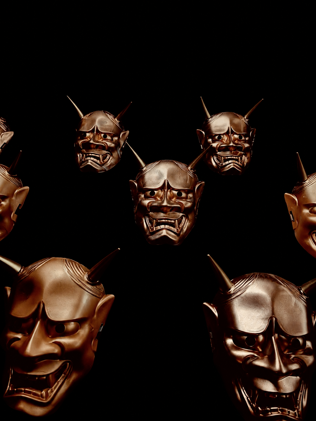 Gold Japanese masks arranged on a dark wall