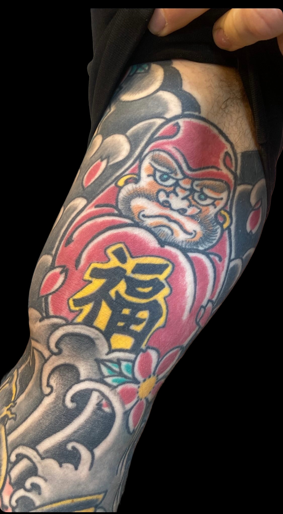 Red Daruma and Japanese wave sleeve tattoo on a solid black background
